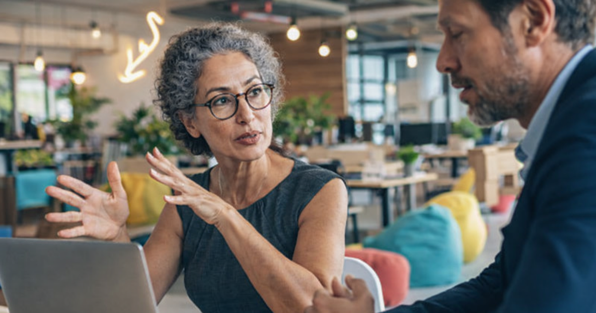 HR professional and employee reviewing outplacement services options together at a modern office table with a laptop open between them